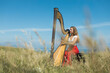 © Westend61 - Young female musician practicing harp in meadow during sunny day