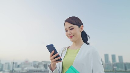 Aufkleber - 都市を背景にスマホを見る女性