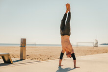 Male Sportsperson Performing Handstand At Beach
