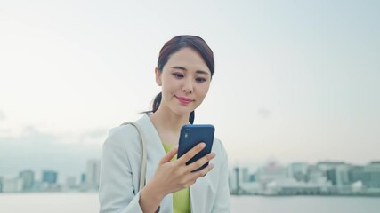 Aufkleber - 都市を背景にスマホを見る女性