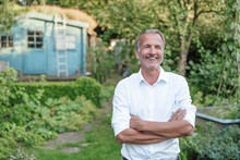 Smiling Man Looking Away With Arms Crossed While Standing In Garden