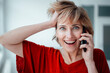 © Westend61 - Businesswoman with hand in hair talking on mobile phone in office