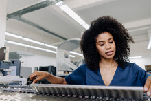 Afro Businesswoman Adjusting Machinery At Printing Industry