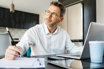 Businessman contemplating while working at table in home office