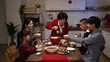 © PRPicturesProduction - senior mistress of the family grandmother standing up and offering food to each member with chopsticks at dinner table during Chinese new year's eve reunion meal at home