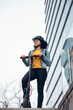 © Westend61 - Woman standing with electric push scooter outside building