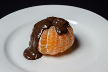 Tangerine In Chocolate On A Black Background. Peeled Tangerine Topped With Melted Chocolate. Fruit Dessert
