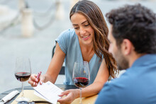 Smiling Woman Showing Postcard To Boyfriend At Restaurant