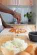 © Westend61 - Man topping pizza with chopped onions in kitchen at home