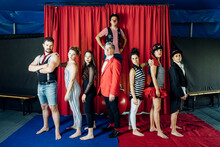 Confident Circus Performers Standing Together In Front Of Red Curtain On Stage