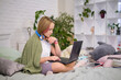 © yavdat - Teenage girl doing homework on the bed. teen girl school student write notes watch video online webinar learn on laptop. distance learning course video conference pc call.