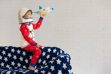 Wall Mural - Happy child astronaut playing with toy rocket at home