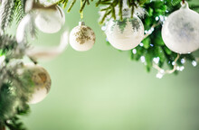 Christmas Decoration With White Christmas Balls And Fir Tree Branches Against Blurred Green Background, Copy Space For Your Product Or Text.