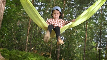 Wall Mural - Small kid in yellow hammock in autumn forest. Childhood with pets concept. UHD 4k video