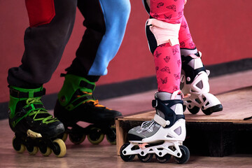 Two pairs of roller skates close-up in the rolling room. The coach teaches the child to roller-skate indoors. Overcome obstacles.