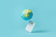 © Yaroslav Danylchenko/Stocksy - Paper globe balancing on debit card