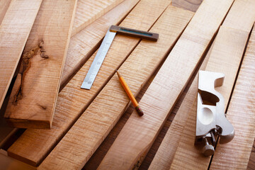 Woodworking with curly maple (or tiger maple) a sought after and prized wood for its beautiful figured grain. Wood working lumber on work bench.Shallow depth of field.