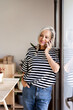 © Eloisa Ramos/Stocksy - Adult woman talking by phone at home office