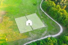Land Plot For Housing On Green Field - Aerial Drone Shot. Topographical Marking Of Two Plots Of Land For Private Residence House Construction. Land Plot Plan With White Graphic House Icon.