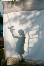 Shadow Of A Girl Behind White Cloth Holding Bird Toy