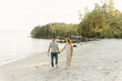 © Luke Liable/Stocksy - Young couple walking on a beach