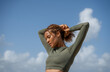 © Jovo Jovanovic/Stocksy - Curly hair woman tying hair before running at the beach