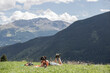 © Marco Reggi/Stocksy - Young student girl reads in the meadow with mountains