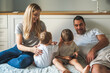 © Aleksandra Jankovic/Stocksy - Family Of Four Sitting On The Bed Together