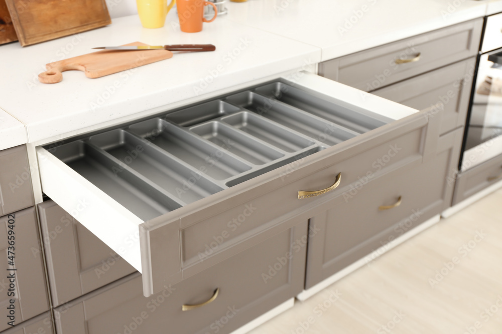 Opened kitchen drawer and utensils in room
