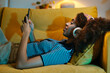 © BONNINSTUDIO/Stocksy - Black female browsing cellphone on couch