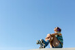 © Jimena Roquero/Stocksy - Girl with roller skates resting under blue sky