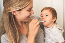 Mother Showing A Baby How To Use A Toothbrush