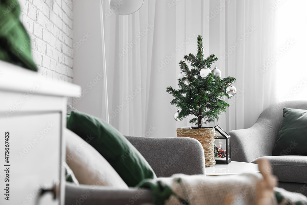 Decorated Christmas tree on table in modern living room