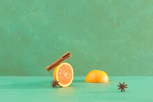 Orange Fruit, Cinnamon Sticks And Anise Stars On Green Table