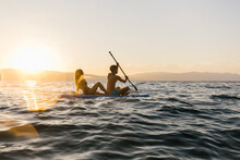Couple On A Sup Board With A Sunset In Background