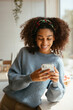 © BONNINSTUDIO/Stocksy - Black female using cellphone in kitchen