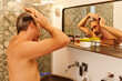© Ivan Gener/Stocksy - Man combing his hair in his bathroom