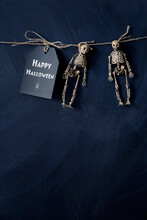 A Note With Two Tiny Skeletons Hanging With String 