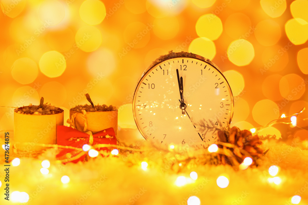 Stylish Christmas clock, decor and snow on table against blurred background