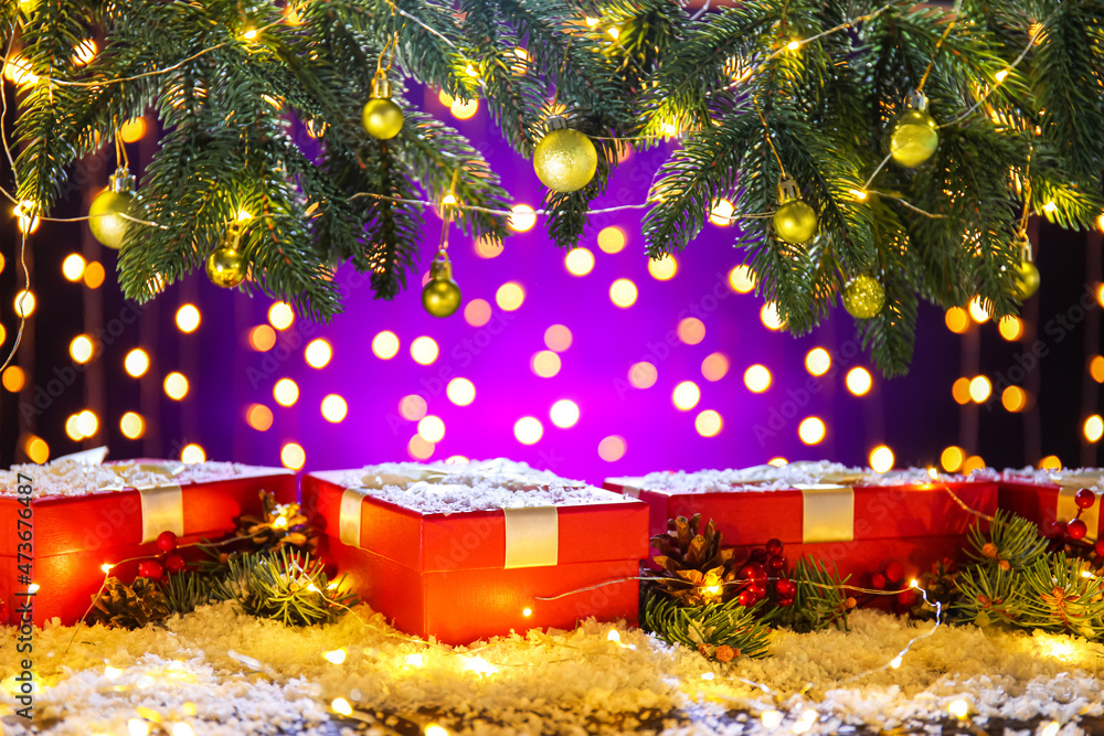 Beautiful Christmas composition with fir branches, snow and gift boxes on table against blurred lights