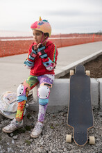 Skateboarding Girl In Safety Gear Sits