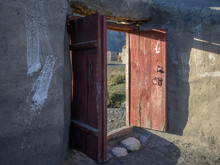 Open Rustic Doorway With Buildings And Human Figure Beyond