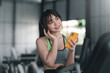 © amnaj - Portrait of young Asian woman with smartphone listening to music in gym.