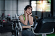 © amnaj - Portrait of young Asian woman with smartphone listening to music in gym.