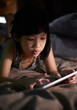 © ChaoShu Li/Stocksy - Asian little girl looking at tablet computer on the bed
