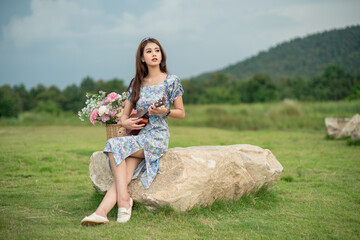 A beautiful Asian woman sitting and playing ukulele in the park