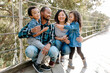 © Erin Brant/Stocksy - Happy family sitting on pedestrian bridge