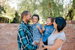 © Erin Brant/Stocksy - Husband and wife holding children outdoors