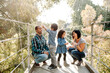 © Erin Brant/Stocksy - Diverse family on sunny pedestrian bridge