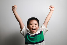 Happy Little Asian Boy Arm Rising Standing Against A Grey Background